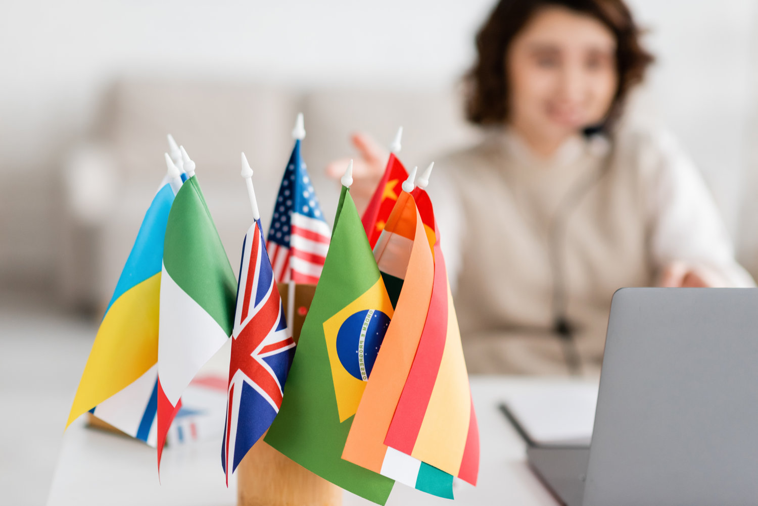 Dolmetscherin am Laptop neben einer Sammlung internationaler Flaggen